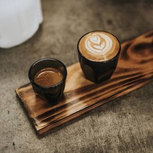A cup of delicious espresso next to a Cappuccino.